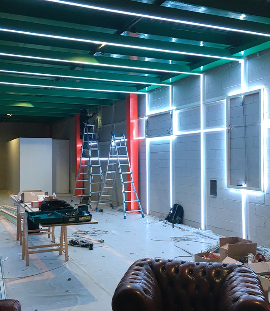 Linea di luce a colori che segue una trave metallica dell'allestimento